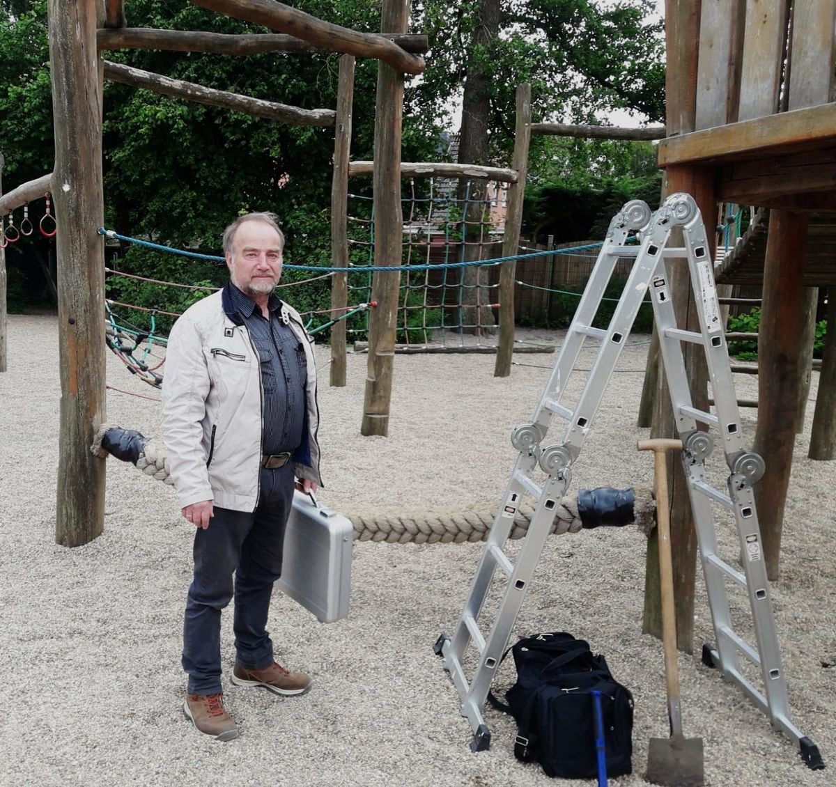 Bernd Rulf mit Prüfkoffer und Leiter auf einem Spielplatz